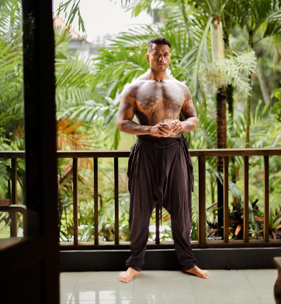 Octavio outdoors on a balcony, tropical greenery behind him.