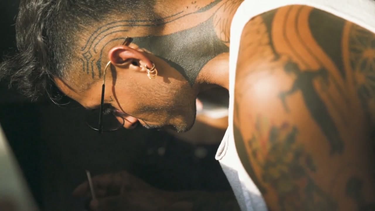 Octavio in profile, head bowed, tattoos across his head and shoulder